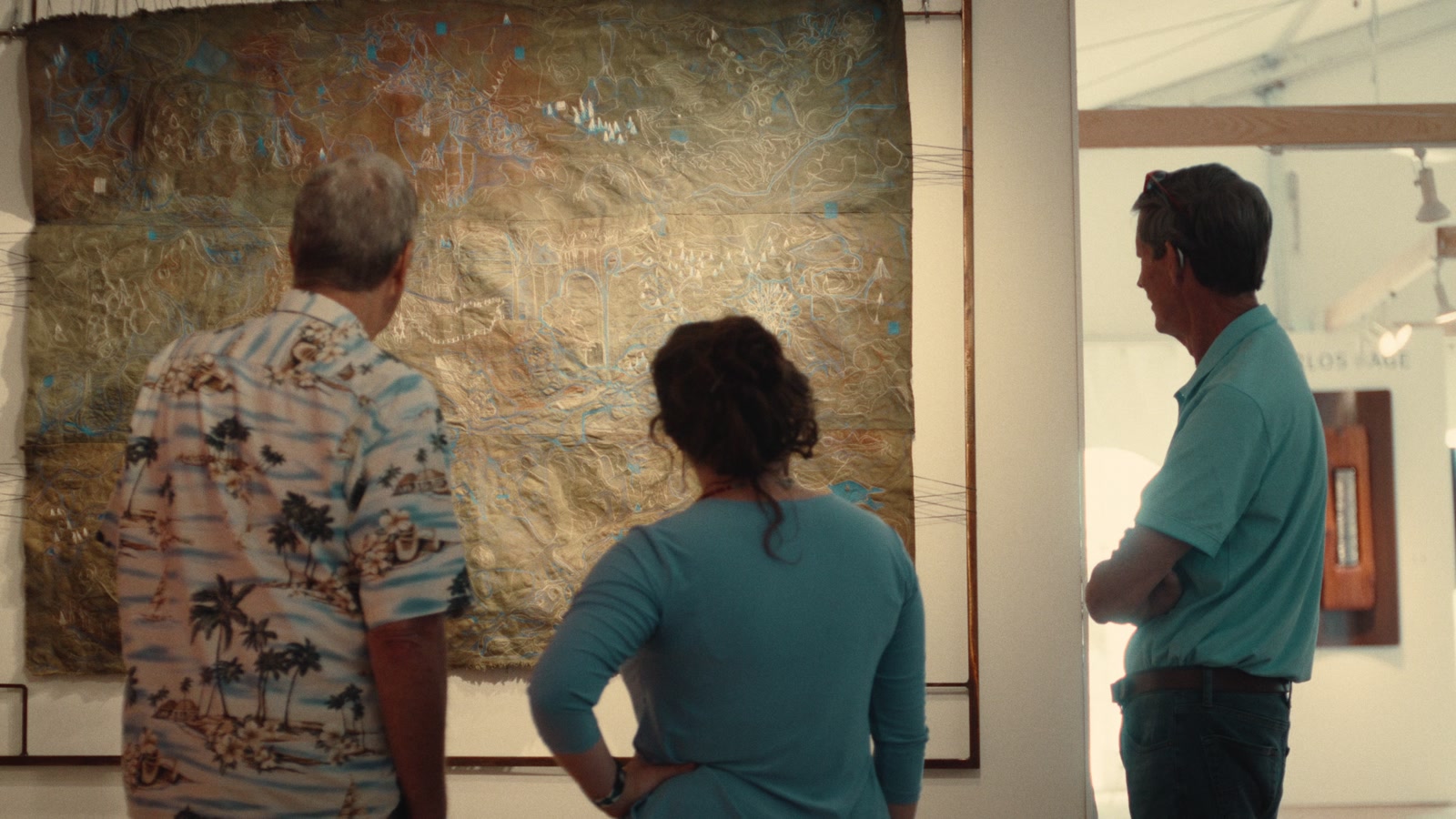 Two visitors looking closely at a painting inside the show